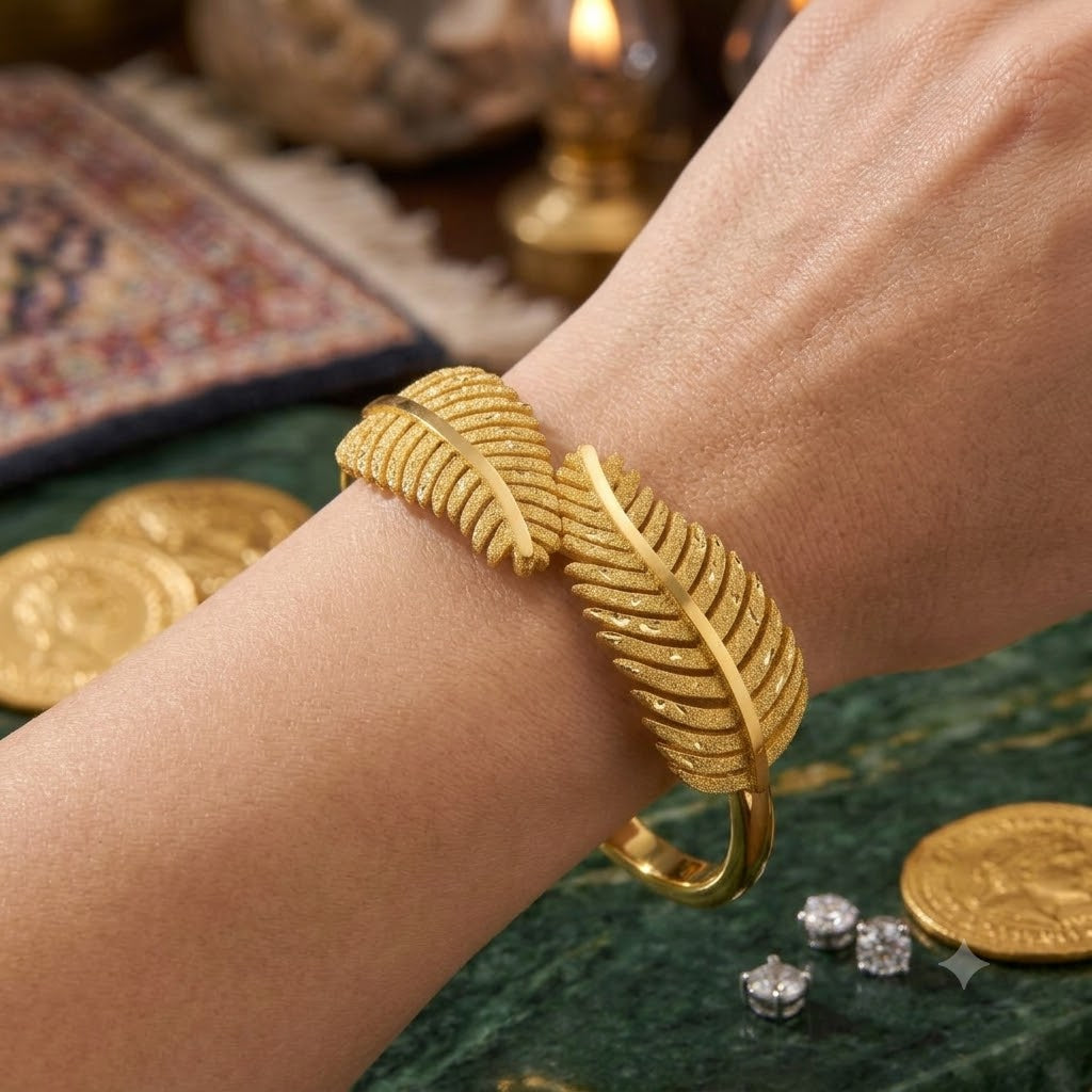 Open cuff / bangle featuring overlapping gold feather or leaf motifs with detailed texture work.
