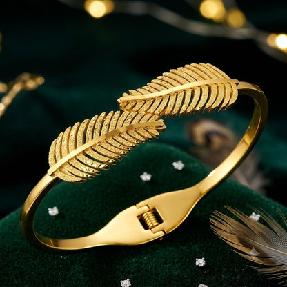 Open cuff / bangle featuring overlapping gold feather or leaf motifs with detailed texture work.