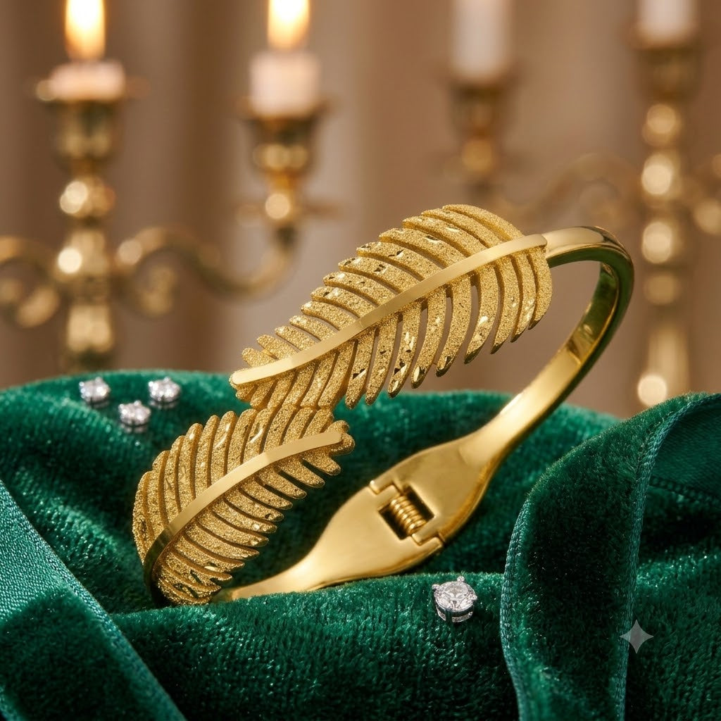 Open cuff / bangle featuring overlapping gold feather or leaf motifs with detailed texture work.