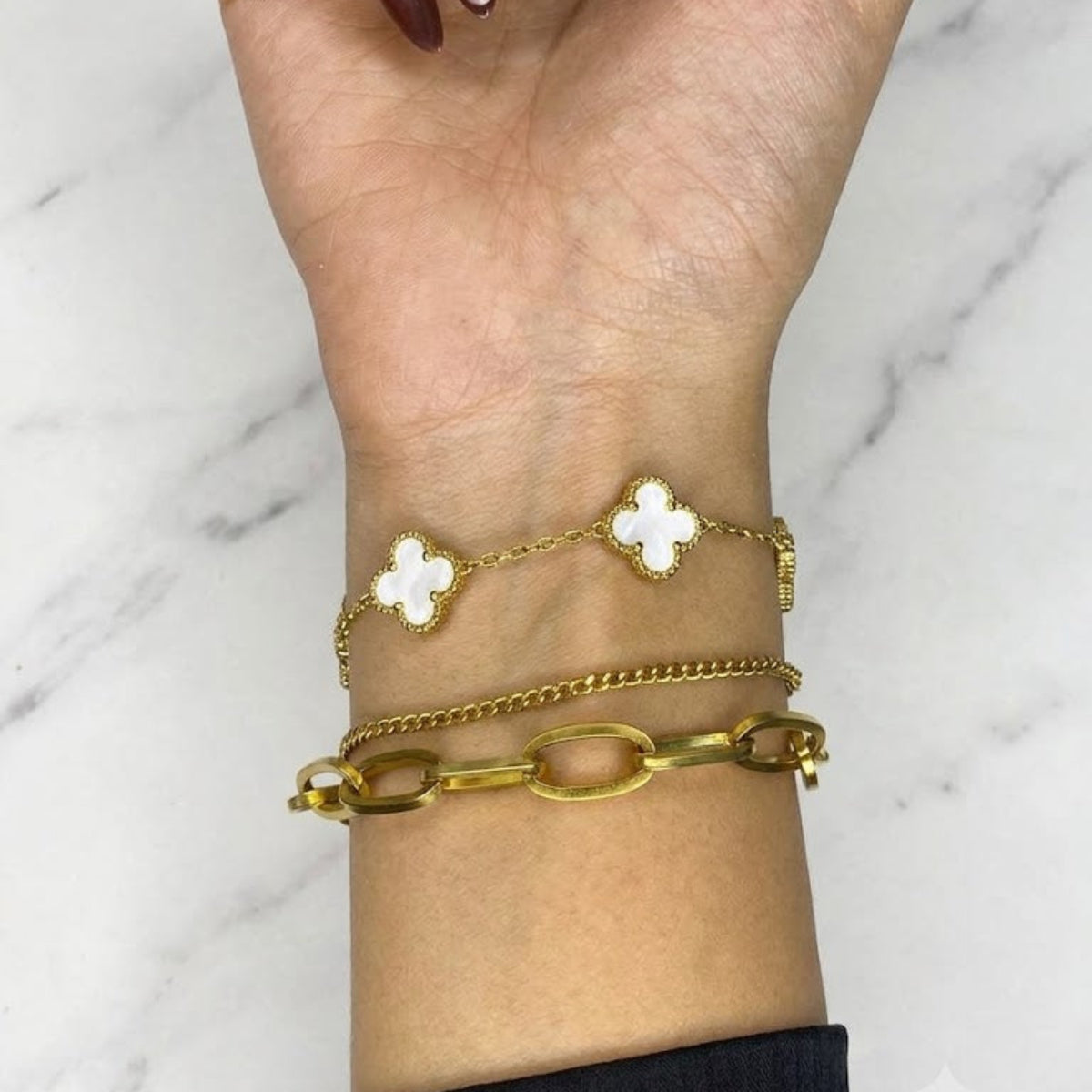 Four-Leaf Clover Bracelet: White enamel clover motif ke sath delicate gold chain design.