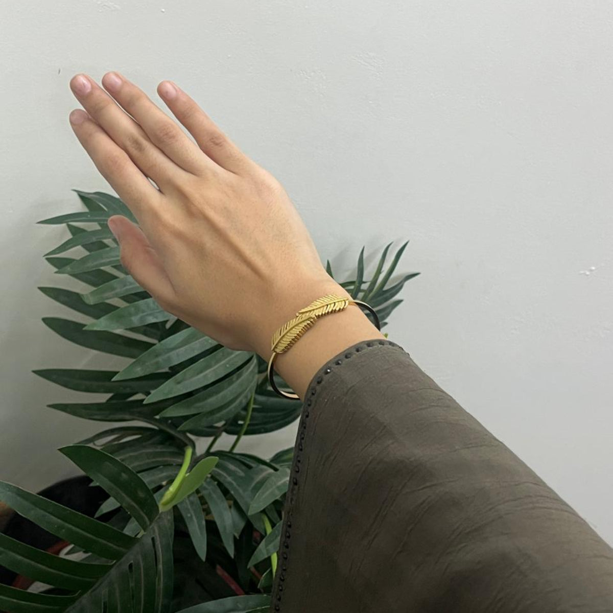 Open cuff / bangle featuring overlapping gold feather or leaf motifs with detailed texture work.