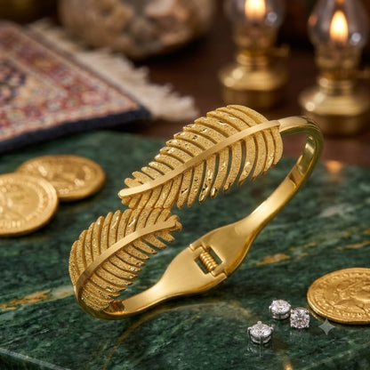Open cuff / bangle featuring overlapping gold feather or leaf motifs with detailed texture work.